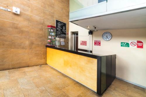 a restaurant with a counter with a clock on the wall at Hotel Kapu, Puebla in Puebla