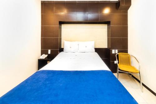 sypialnia z łóżkiem i żółtym krzesłem w obiekcie Hotel Kapu w mieście Puebla