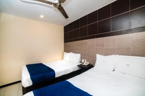 two beds in a room with white and blue sheets at Hotel Kapu, Puebla in Puebla