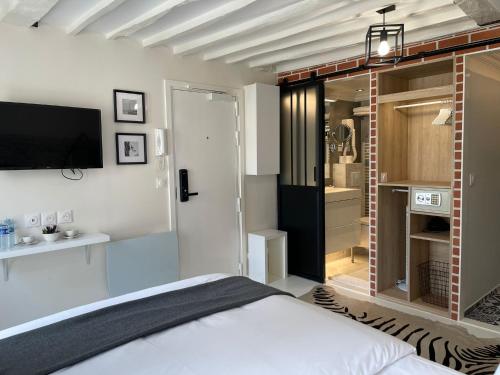 une chambre avec un lit et une télévision au mur dans l'établissement Studio Beaubourg Marais, à Paris