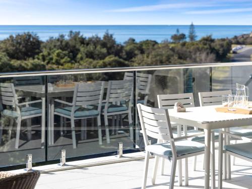 a balcony with chairs and a table and the ocean at Cove 603 in Forster