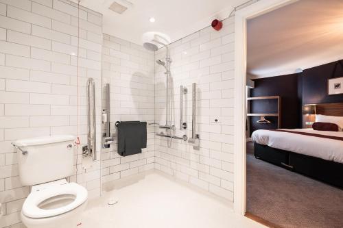 a bathroom with a toilet and a shower and a bed at Miller & Carter Brighton by Innkeeper's Collection in Brighton & Hove