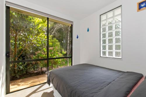 a bedroom with a bed and a large window at Green Oasis - Mangawhai Heads Holiday Home in Mangawhai