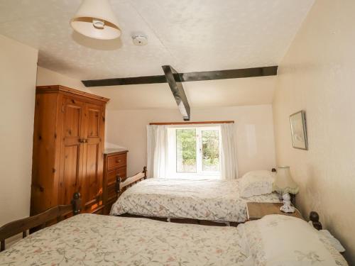 a bedroom with two beds and a window at Mill Cottage in Tintagel