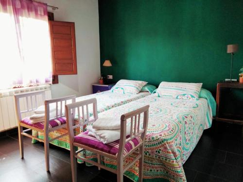 a green bedroom with two beds and two chairs at En Huerto de Catalina in Fuentes de Béjar