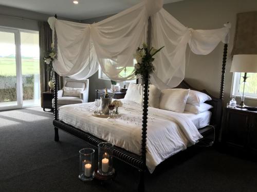 Dormitorio con cama con dosel y velas en Chateau Pritchard, en Springston