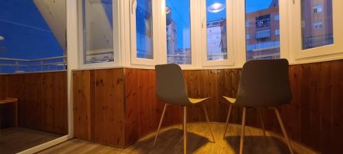 two chairs sitting in a room with windows at Oro Apartments Tirana in Tirana