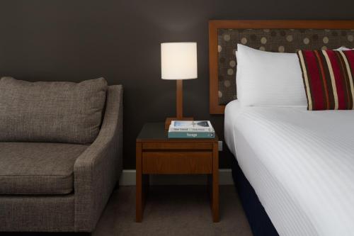 a bedroom with a bed and a chair and a lamp at Yarra Valley Lodge in Wonga Park