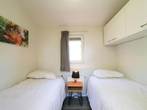 - 2 lits dans une chambre avec une table dans l'établissement Modern chalet with AC, located at a playground, à Hoenderloo