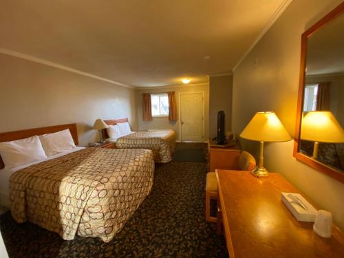 a hotel room with two beds and a table at Aspen Motor Inn in Drayton Valley