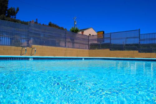 a swimming pool with blue water in front of a fence at Best 5 Motel in Salinas