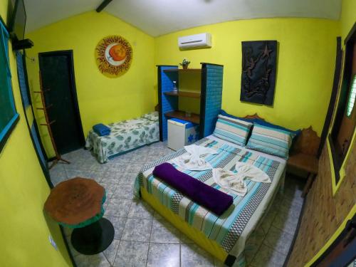 - une chambre avec un lit et un mur jaune dans l'établissement Pousada A Nave - Itaunas-ES, à Itaúnas