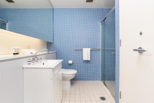 a bathroom with a toilet and a shower with blue tiles at Darling Harbour Apartment near King St Wharf in Sydney