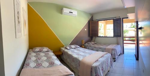 a room with two beds and a yellow wall at Casa em Antunes Maragogi Condomínio Beira Mar in Maragogi