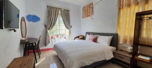 a bedroom with a bed and a window and a television at Auntie's Flowers Homestay in Changbin