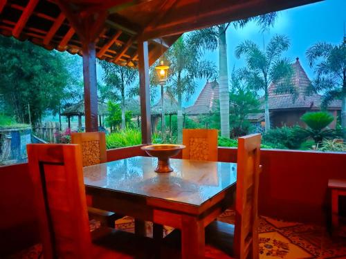 a table and chairs on a porch with a view of a resort at Villa Sindoro Village in Wonosobo