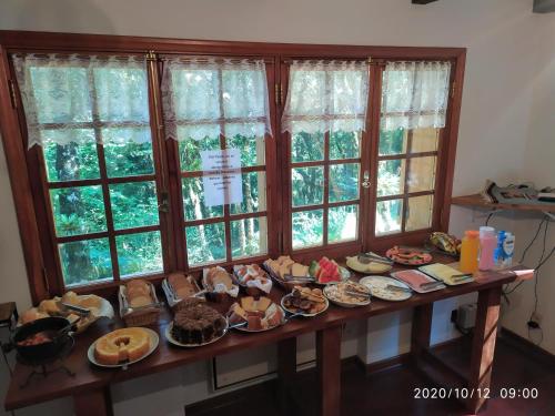 uma mesa cheia de pratos à frente das janelas em Refúgio do Selado em Monte Verde