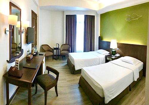 um quarto de hotel com duas camas e uma secretária em Krungsri River Hotel em Phra Nakhon Si Ayutthaya