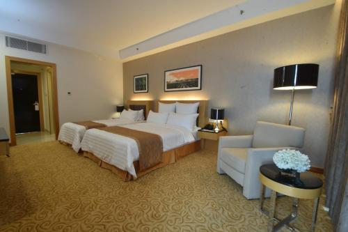 a hotel room with a large bed and a chair at Tenera Hotel in Bangi