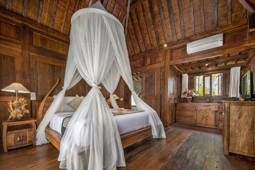 a bedroom with a bed with a mosquito net at Madani Antique Villas in Ubud