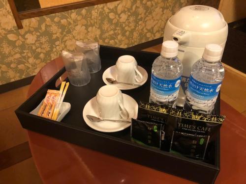 a tray with cups and plates and bottles of water at ホテルアイエス in Yokohama