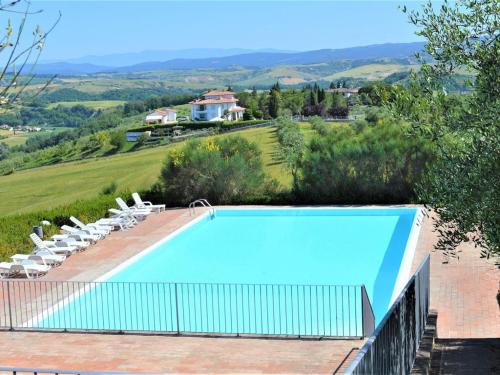 a large swimming pool with chairs and a house at Belvilla by OYO Appartamento Panorama in Asciano