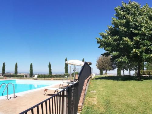 a swimming pool with a black fence next to a yard at Belvilla by OYO Appartamento Dante in Serre di Rapolano