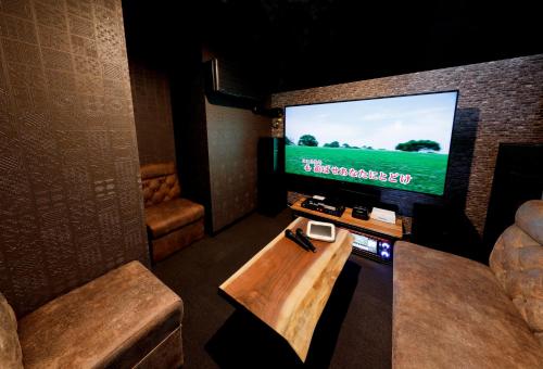 a room with a tv and a table and a couch at 暖炉之宿 コンセプトハウス星田 in Katano