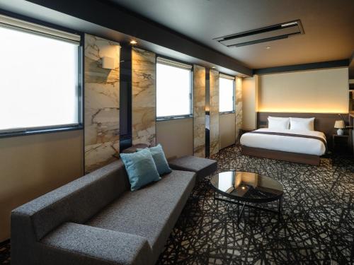 une chambre d'hôtel avec un canapé et un lit dans l'établissement Hotel Act Garden HAMAMATSU, à Hamamatsu