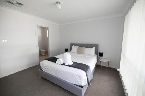 a bedroom with a large bed with white sheets and pillows at Wagga Apartments #8 in Wagga Wagga