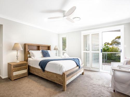 a white bedroom with a bed and a window at Havenwood - Pet Friendly - Spa & Community Pool in Callala Beach