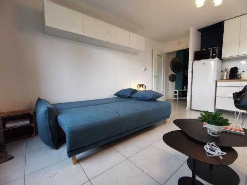 a bedroom with a blue bed and a kitchen at CÔTÉ GARE - Gare - Centre-ville - Parking - Netflix - Wifi - Disney+ - Terrasse in Annecy