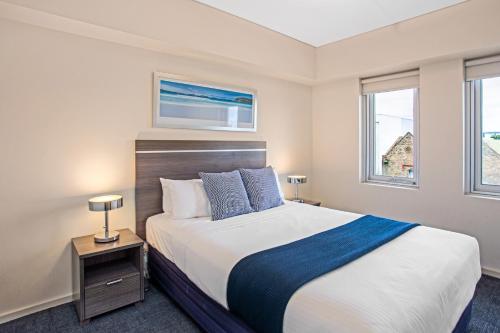 a bedroom with a large bed and two windows at Hume Serviced Apartments in Adelaide