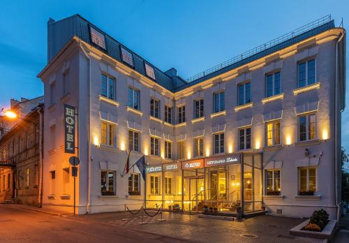 un gran edificio blanco con luces encendidas en Ratonda Centrum Hotels en Vilna