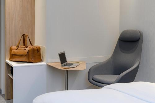 um quarto com uma cadeira e um computador portátil sobre uma mesa em Holiday Inn Express - Regensburg, an IHG Hotel em Regensburg