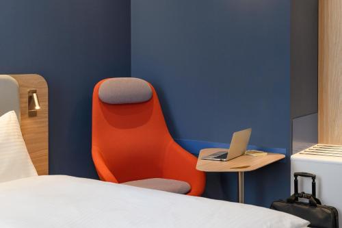 a room with a bed and a chair with a laptop at Holiday Inn Express - Regensburg, an IHG Hotel in Regensburg