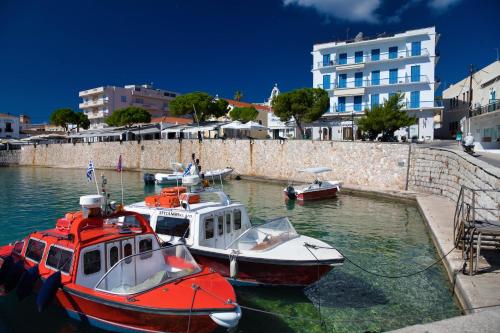 three boats are docked in the water near a building at Aria Apartments in Spetses