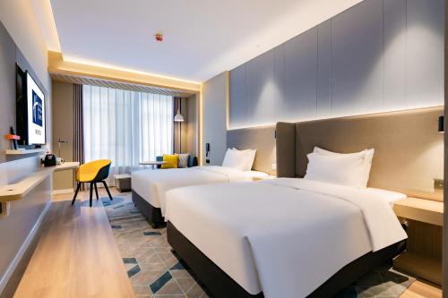 Habitación de hotel con 4 camas y escritorio. en Holiday Inn Express Xi'an High Tech Zone North, an IHG Hotel, en Xi'an