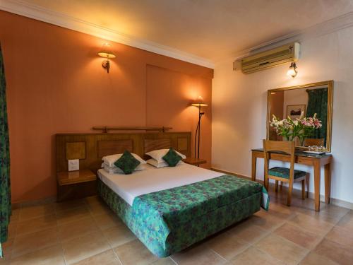 1 dormitorio con cama, mesa y espejo en Bellflower Alidia Beach Resort en Baga