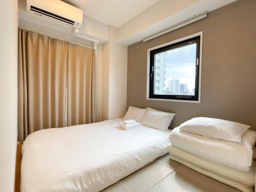 1 dormitorio con 2 camas y ventana en The Light Inn Tokyo, en Tokio