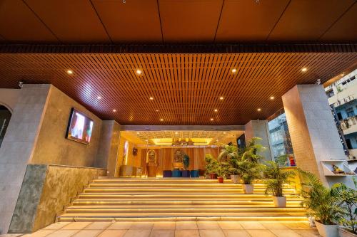 a lobby of a building with stairs and plants at Hotel Jagadish International-Sankey Road in Bengaluru