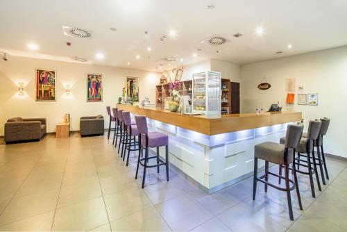 a bar with purple stools in a waiting room at Hunguest Hotel Gyula in Gyula
