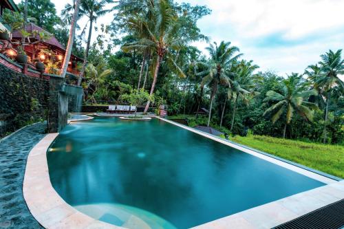 a swimming pool in a resort with palm trees at Umasari Rice Terrace Villa in Tabanan