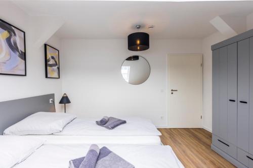 a white bedroom with two beds and a lamp at Glück Auf Appartements Kaiserstraße Mülheim in Mülheim an der Ruhr