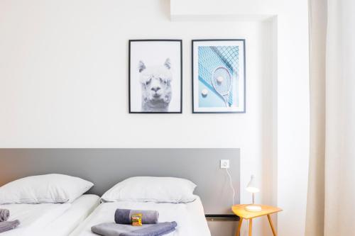 two beds in a bedroom with three pictures on the wall at Glück Auf Appartements Kaiserstraße Mülheim in Mülheim an der Ruhr