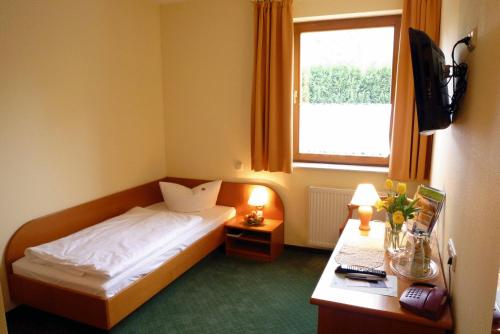 a bedroom with a bed and a desk and a window at Landhotel Dresden in Dresden