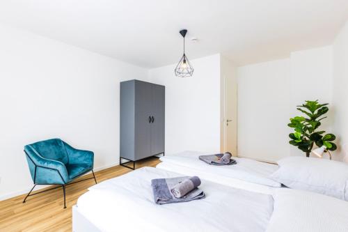 two beds in a room with a blue chair at Glück Auf Appartements Kaiserstraße Mülheim in Mülheim an der Ruhr