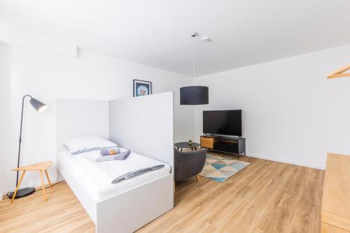a white bedroom with a bed and a television at Glück Auf Appartements Kaiserstraße Mülheim in Mülheim an der Ruhr