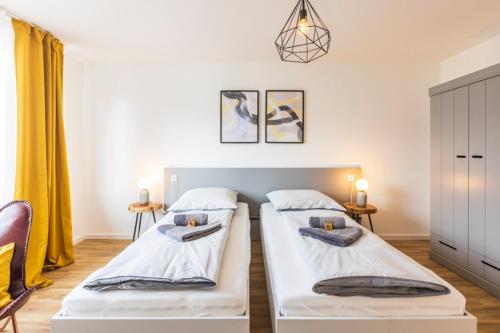 two beds in a room with yellow curtains at Glück Auf Appartements Kaiserstraße Mülheim in Mülheim an der Ruhr