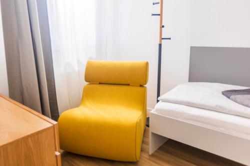 a yellow chair in a room next to a bed at Glück Auf Appartements Kaiserstraße Mülheim in Mülheim an der Ruhr